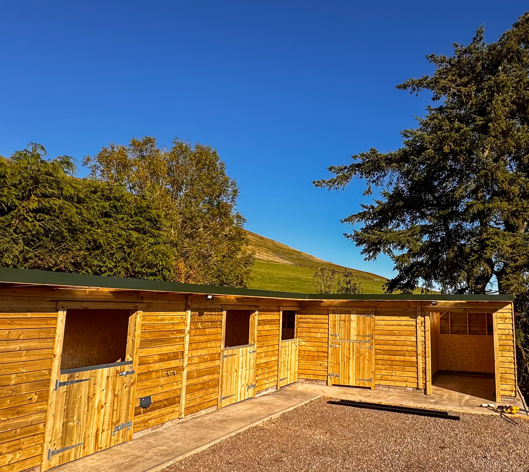 Completed custom stable complex with Scottish hillside backdrop